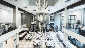 A spacious hotel lobby with multiple dining areas, a central chandelier, and a view of the upper floor. - Hampton Inn & Suites Fairfield (Fairfield)