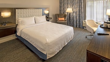 Habitación de hotel con una cama grande, un escritorio, una silla, una lámpara y un teléfono.