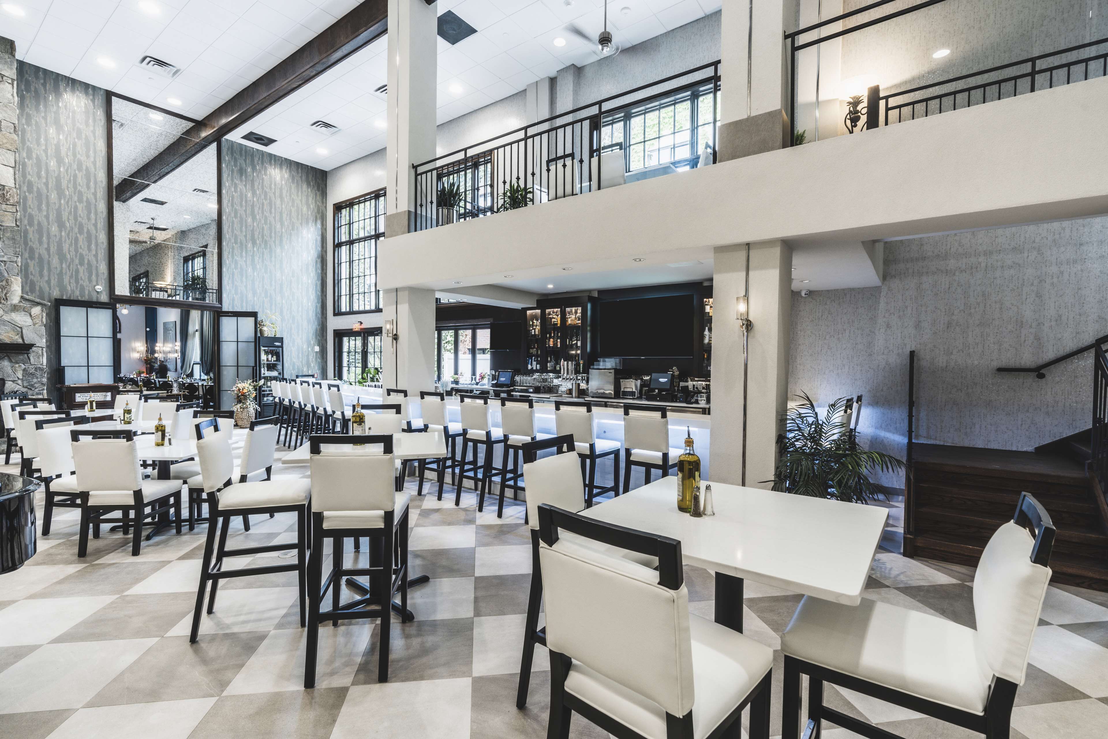 A spacious indoor area with multiple dining tables and chairs, a kitchen area, and a staircase leading to an upper level.