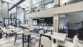 A spacious indoor area with multiple dining tables and chairs, a kitchen area, and a staircase leading to an upper level.