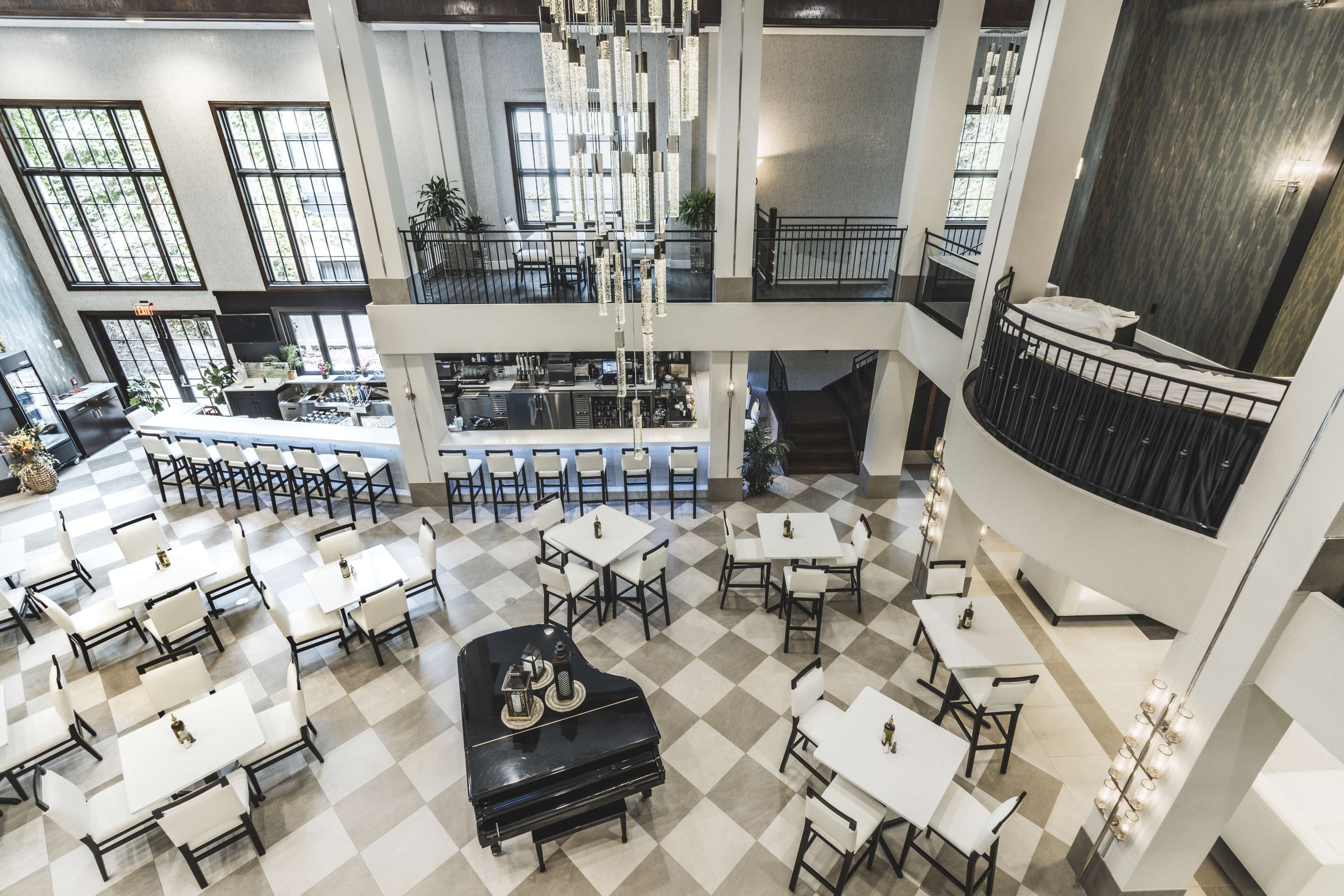 A spacious multi-level restaurant with a checkered floor, white tables, and a piano.