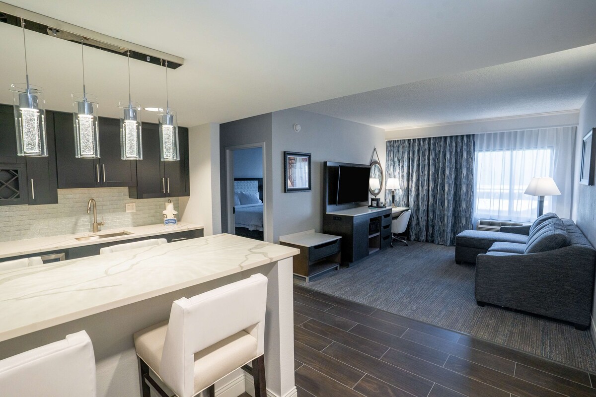 Une chambre d’hôtel moderne équipée d’un coin cuisine, d’une table à manger, d’un canapé et d’un téléviseur.