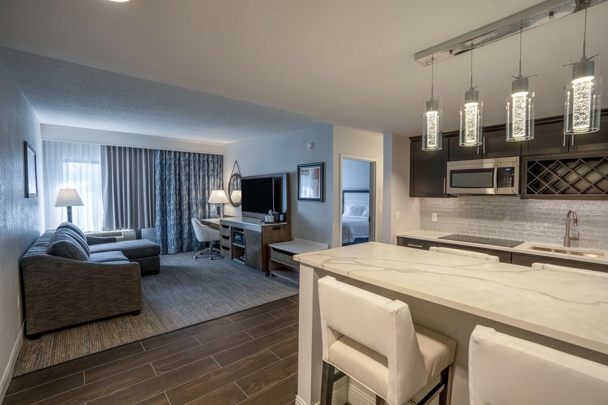 Une chambre d’hôtel moderne comprenant un espace de vie, un coin repas et une cuisine.