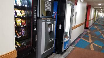 A hotel corridor with vending machines, ice cubes, and a patterned carpet.