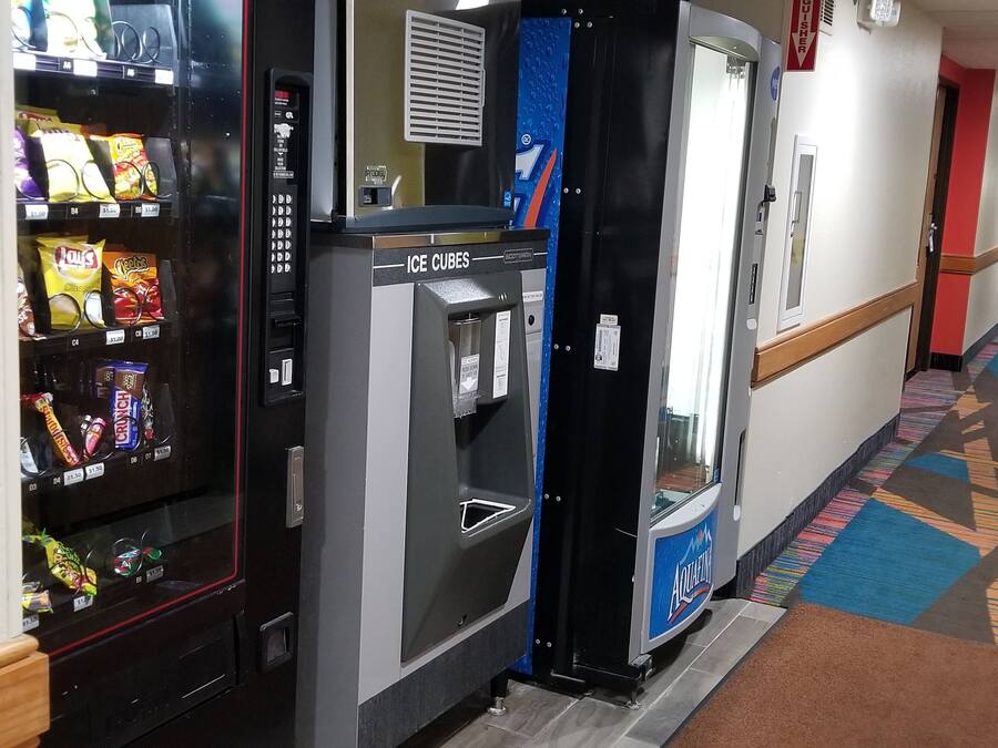 A hotel corridor with vending machines, ice cubes, and a patterned carpet.