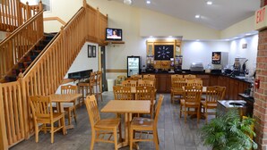 Un restaurant doté de mobilier en bois, d’un téléviseur, d’un réfrigérateur et d’une machine à café.