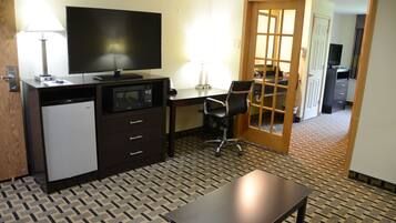 Een hotelkamer met een bureau, stoel, televisie en een magnetron.