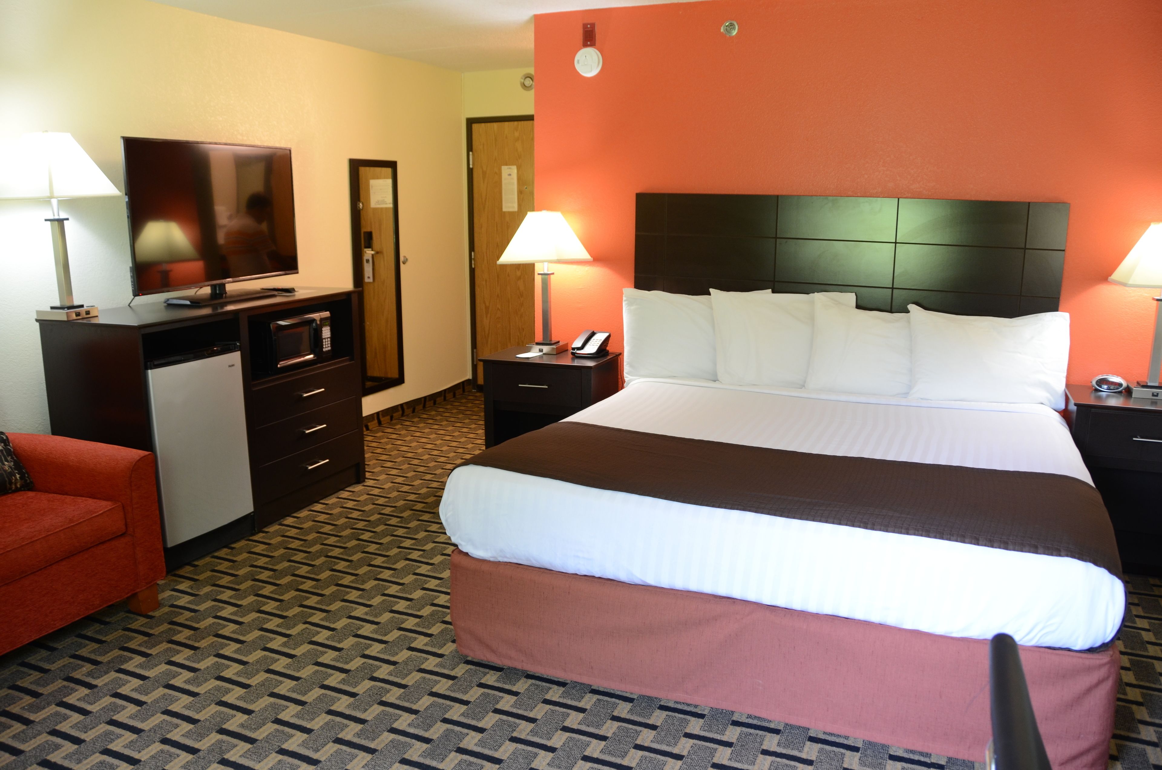 Habitación de hotel con una cama grande, televisor, escritorio con computadora y dos lámparas.