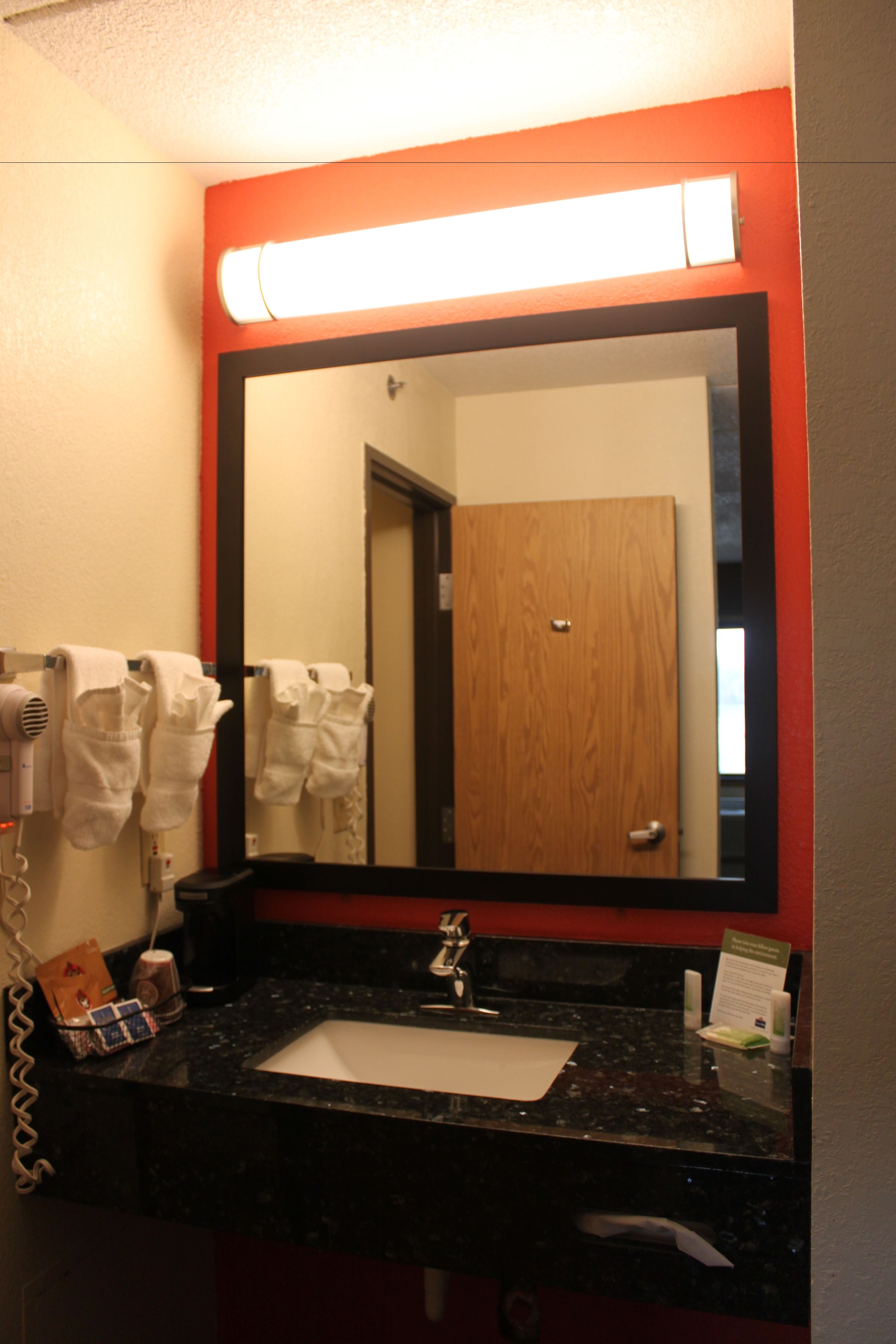 A bathroom with a large mirror, a sink, and a hairdryer.