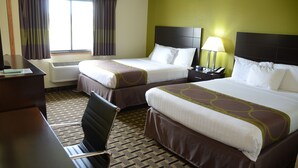 Une chambre d’hôtel avec deux lits, un bureau, une chaise, une lampe et une fenêtre avec des rideaux.
