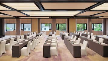 A conference room with long tables and chairs, large windows, and a carpeted floor.