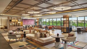 A spacious lobby with a large sofa, multiple seating areas, and a view of greenery through large windows. - Renaissance Shanghai Hongqiao (Shanghai)