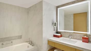 A modern bathroom with a bathtub, a large mirror, and a vanity with a sink.