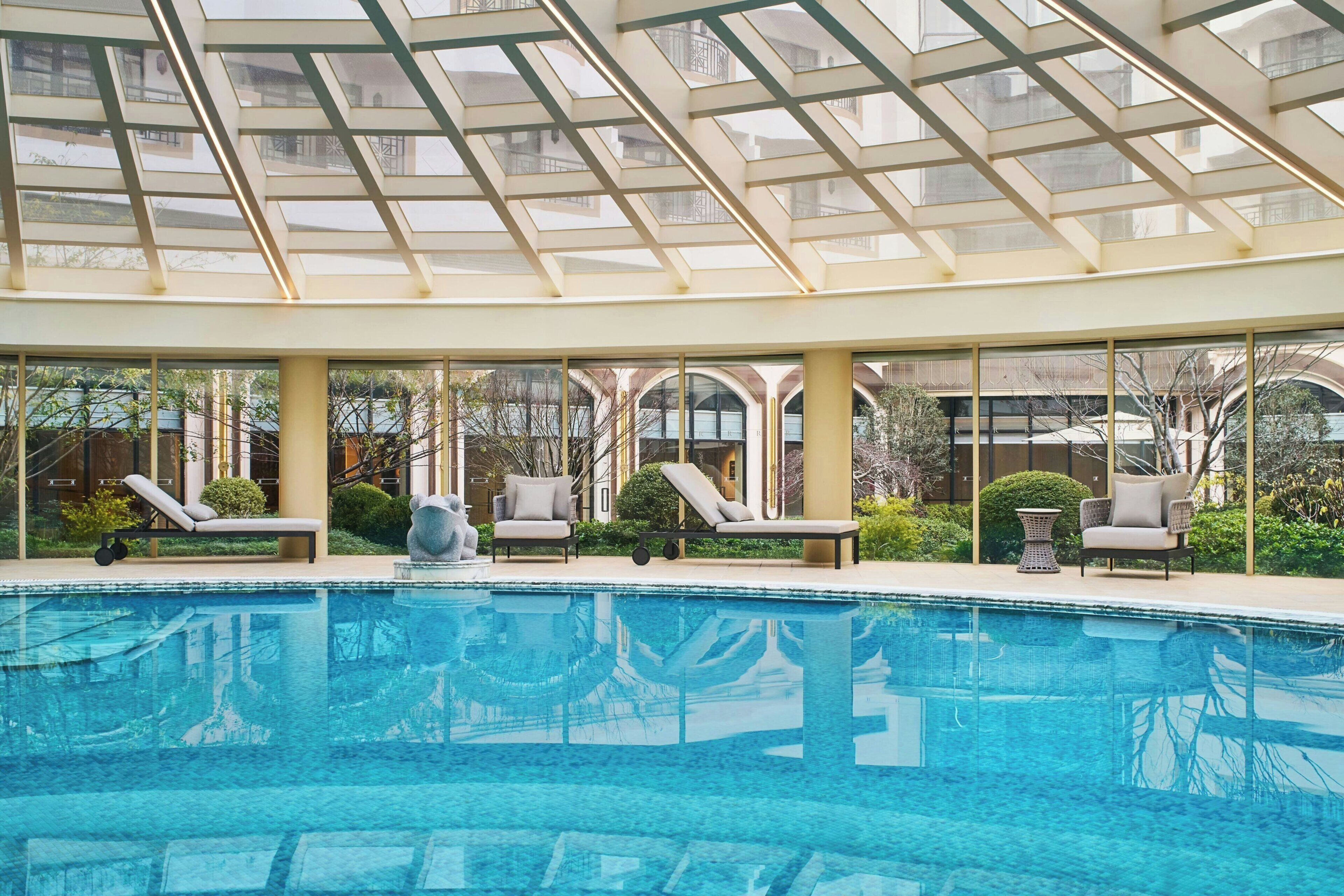 Een binnenzwembad, ligstoelen bij het zwembad, badmeesters op locatie