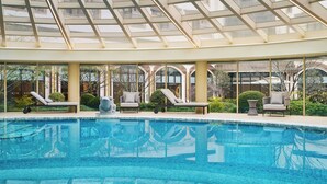 A swimming pool with lounge chairs and a glass ceiling. - Renaissance Shanghai Hongqiao (Shanghai)