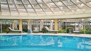 Een binnenzwembad, ligstoelen bij het zwembad, badmeesters op locatie