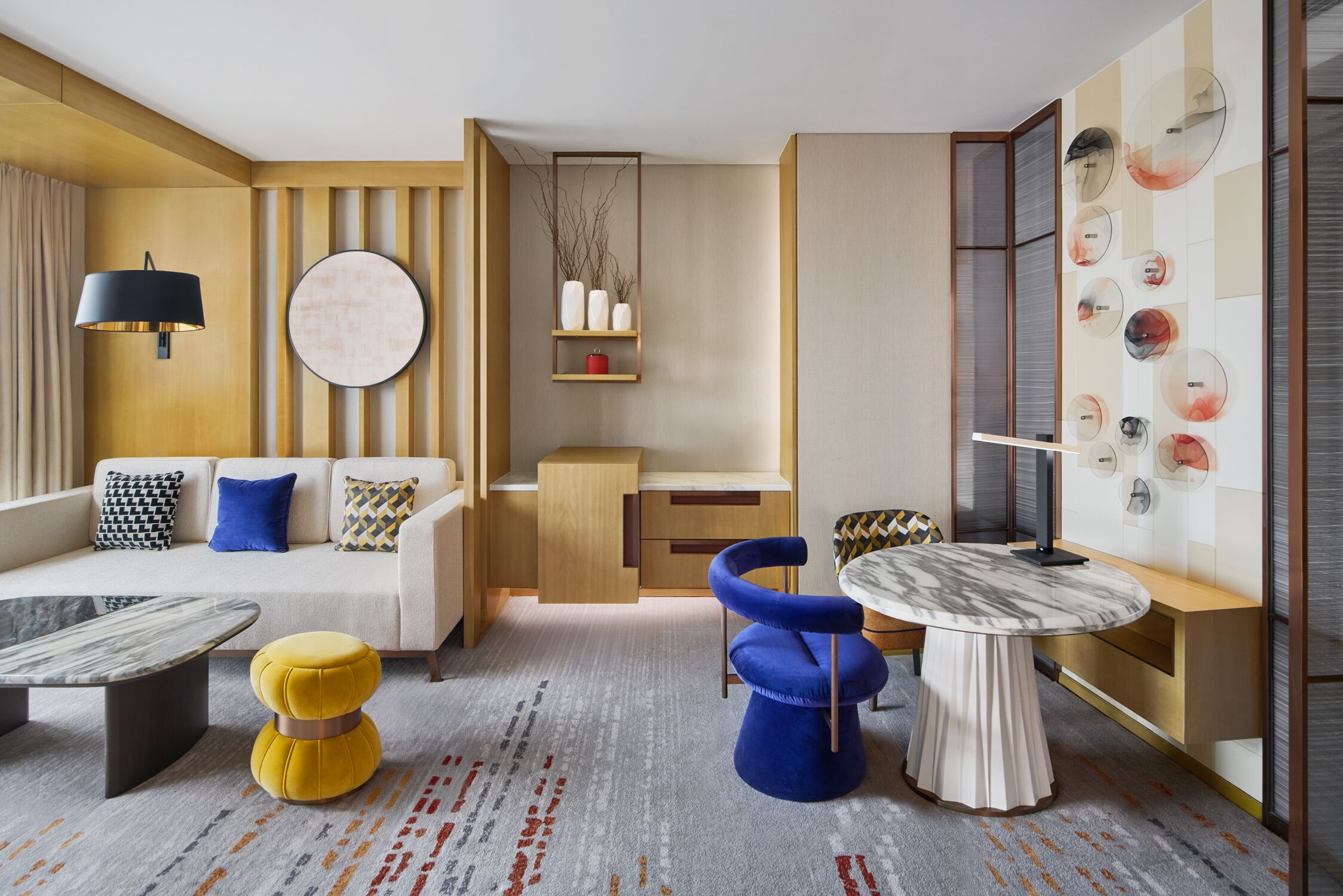 Una sala de estar moderna con un sofá, una mesa redonda de centro, una silla azul y una mesa de comedor.