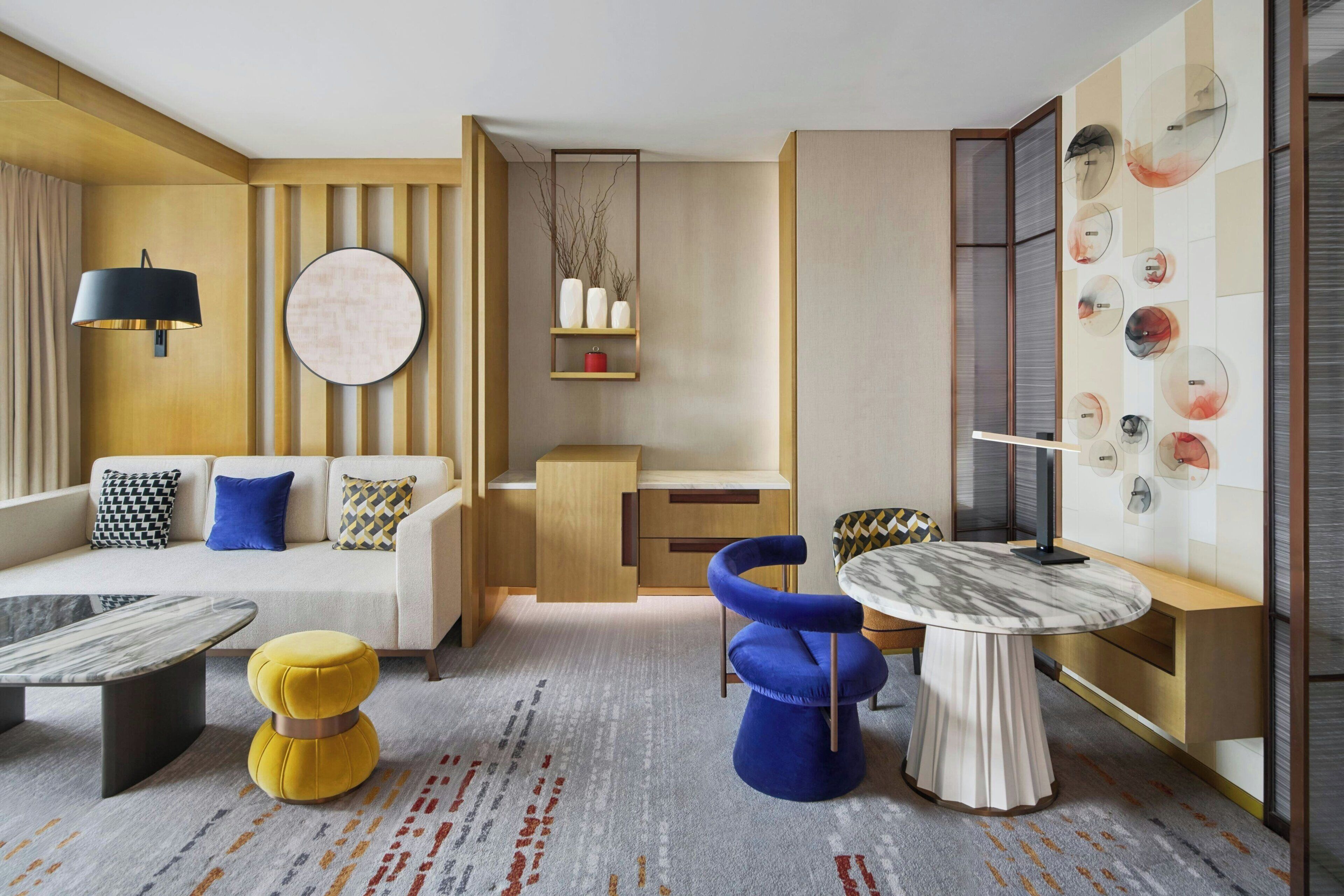 Un salon moderne comprenant un canapé, une table basse, un pouf et un coin repas avec une table et des chaises.