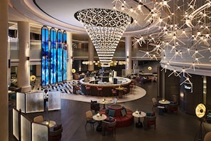 A modern hotel lobby with a central bar, seating areas, and a large decorative light fixture. - Renaissance Shanghai Hongqiao (Shanghai)