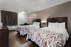 A hotel room with two beds, a desk, a chair, a radiator, and a window with curtains. - Red Roof Inn & Suites Savannah Airport (Pooler)