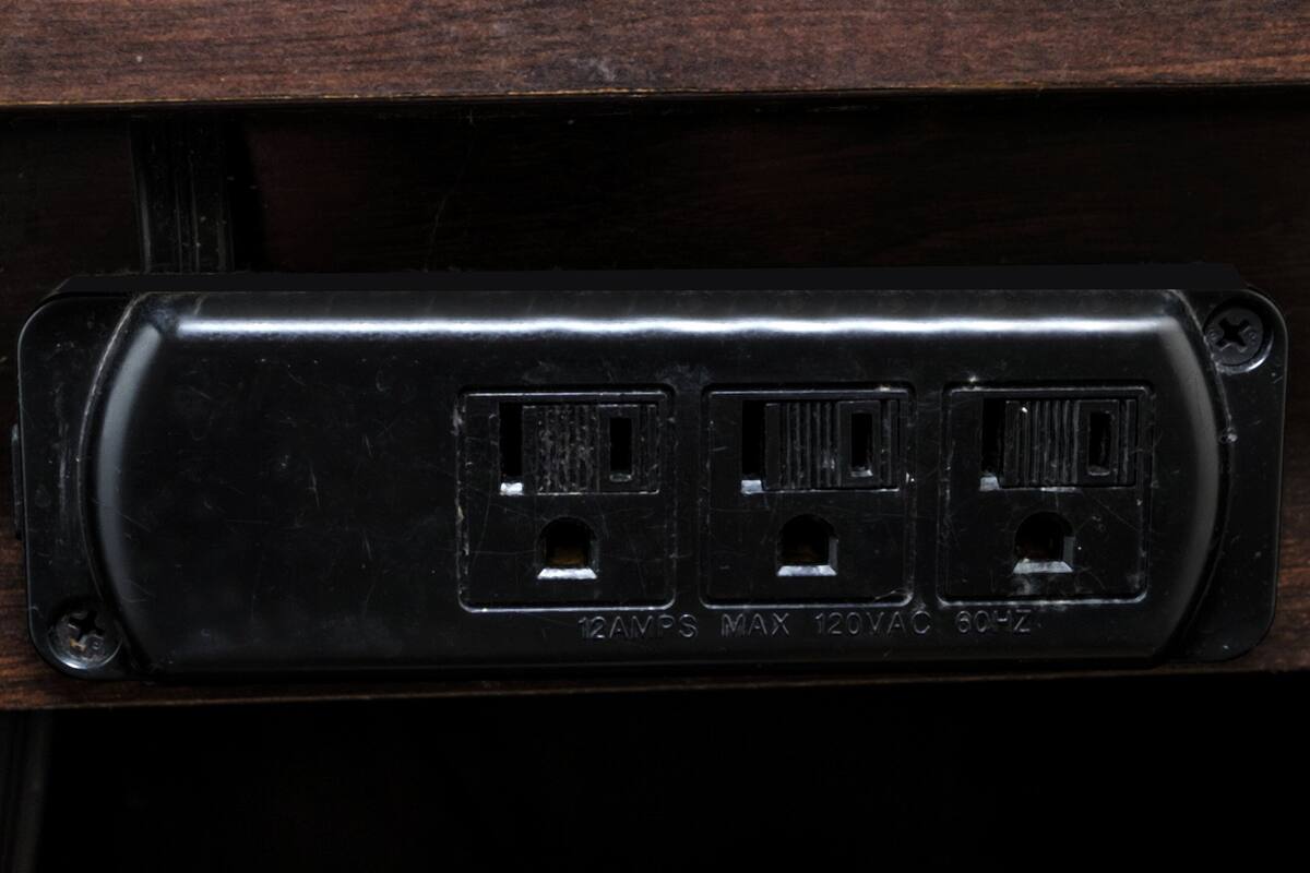 Presta d'electricitat negra amb tres connexions, amb l'etiqueta '12AMP MAX 120VAC 60HZ'.