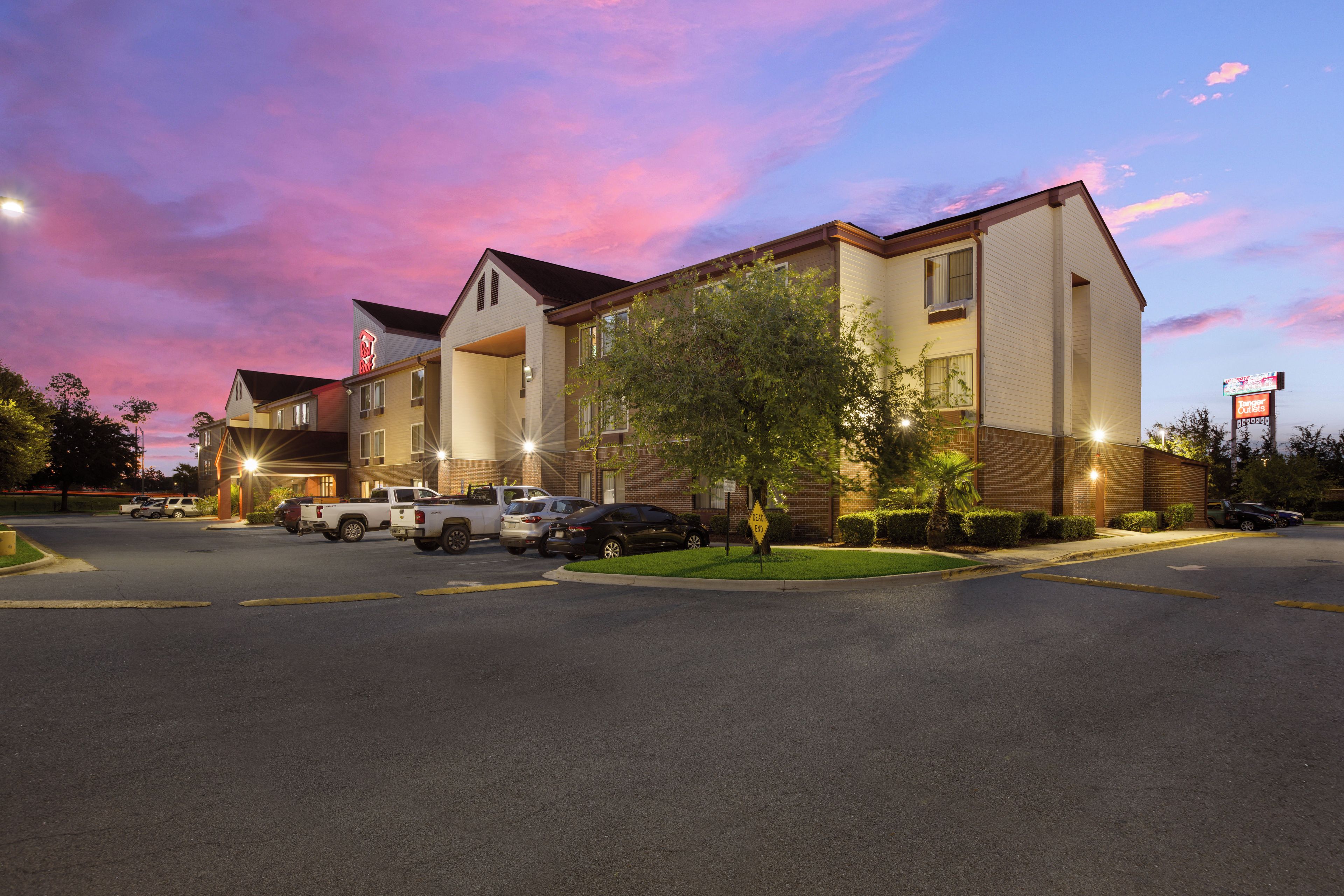 A hotel with multiple stories, parking lot, and a clear sky.