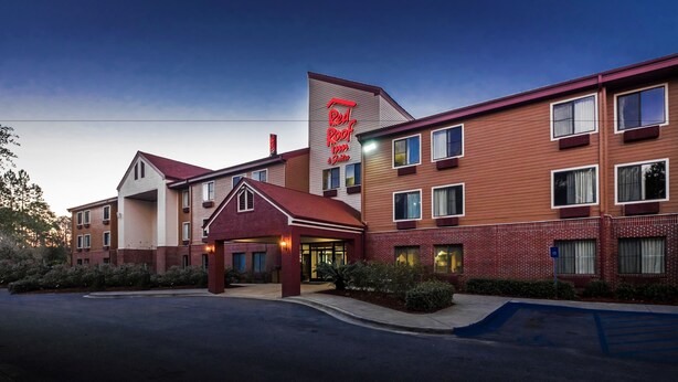 A Red Roof Inn with a brick facade, multiple windows, and a well-lit entrance.