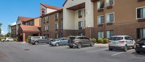 Un hotel con diversi posti auto, facciata in mattoni e cielo azzurro.