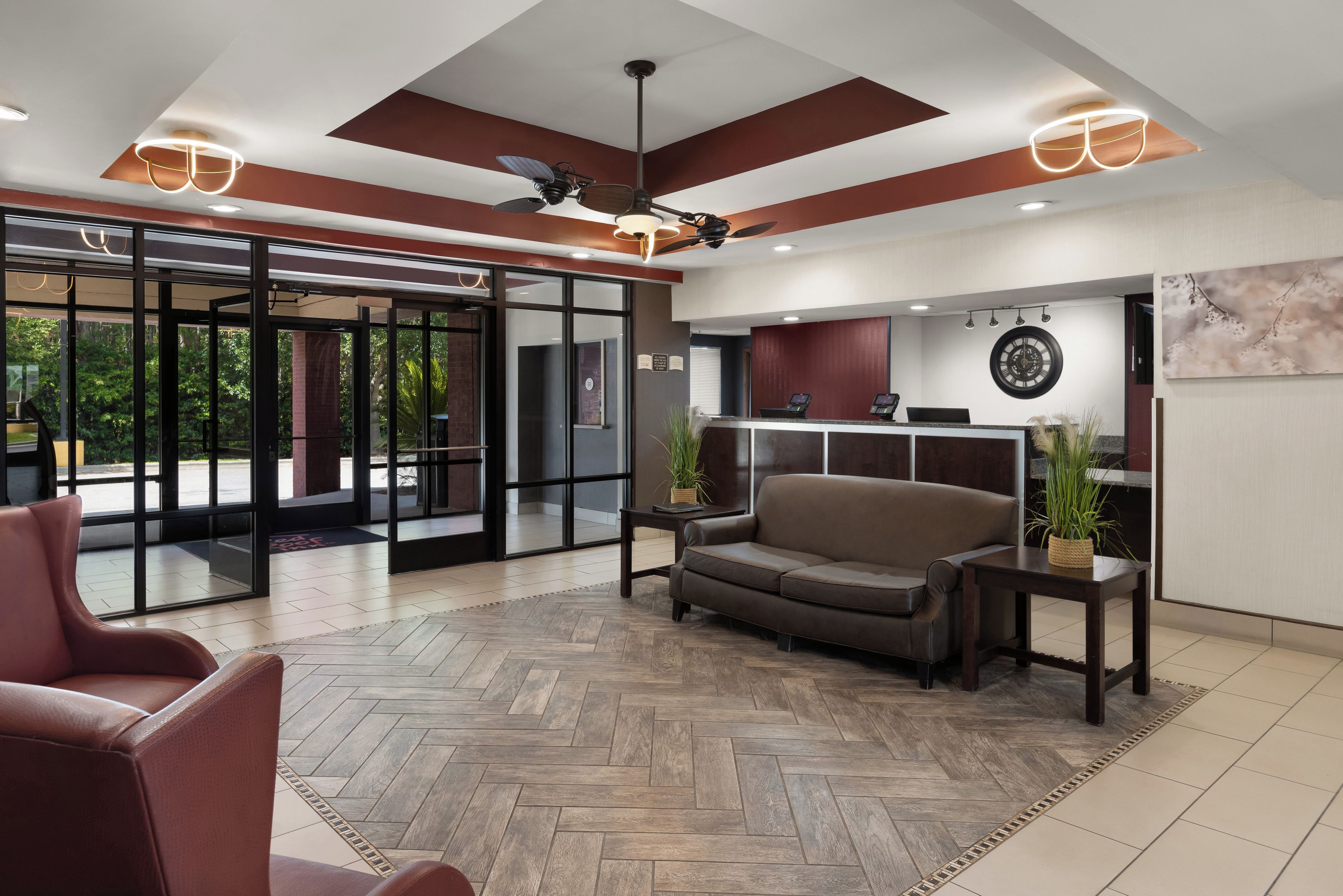 A modern lobby with a herringbone floor, a sofa, a coffee table, and a reception desk with a phone.