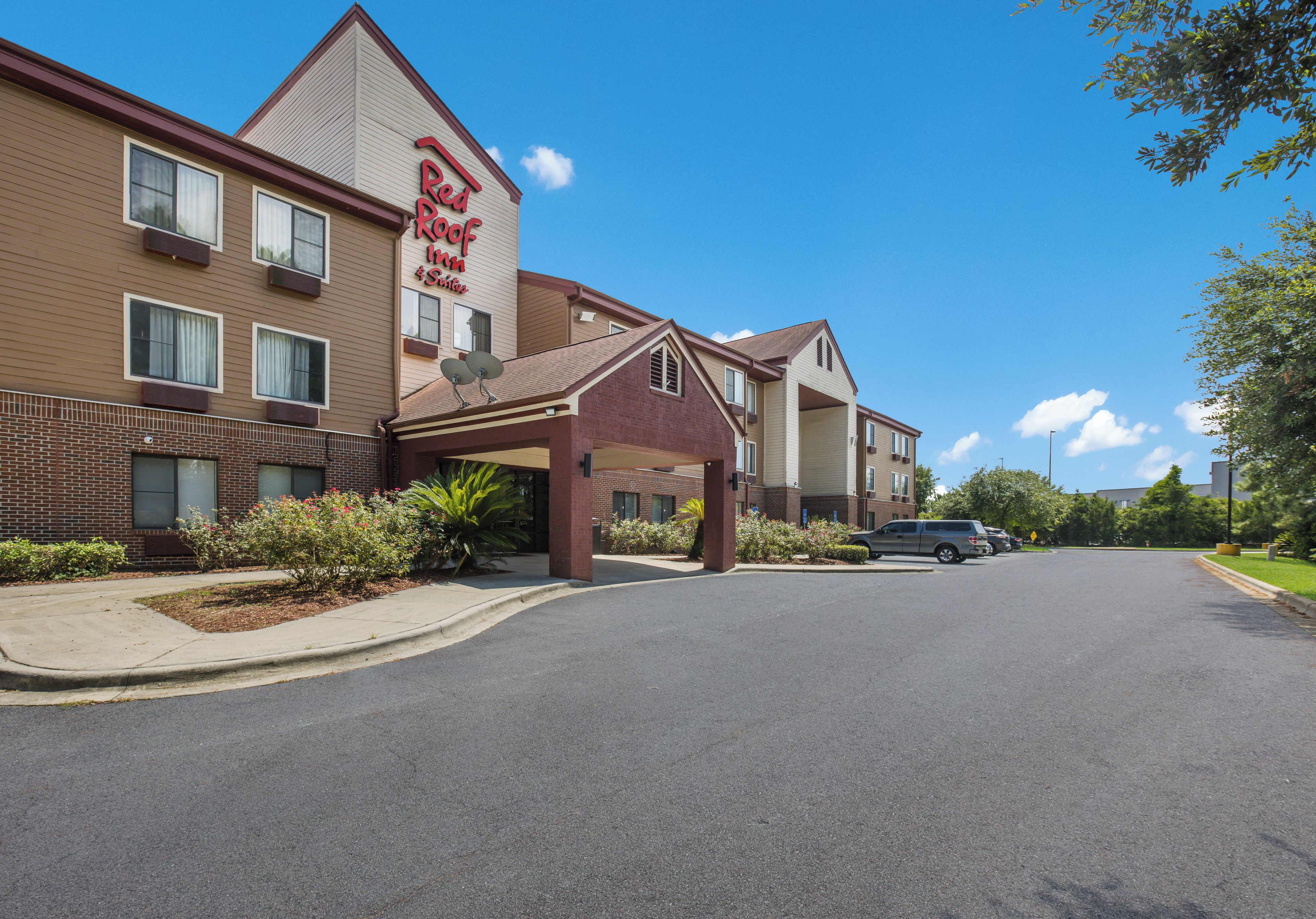 A Red Roof Inn & Suites with a covered entrance, a brick facade, and a parking lot.