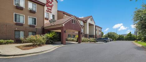 A Red Roof Inn & Suites with a covered entrance, a brick facade, and a parking lot.