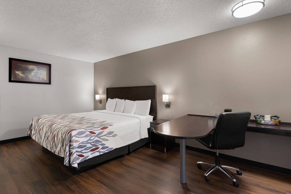 A hotel room with a bed, a desk, and a chair.