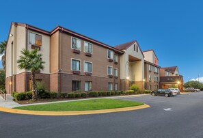 Un edificio residencial de varios pisos con fachada de ladrillo, múltiples ventanas y un césped bien cuidado.