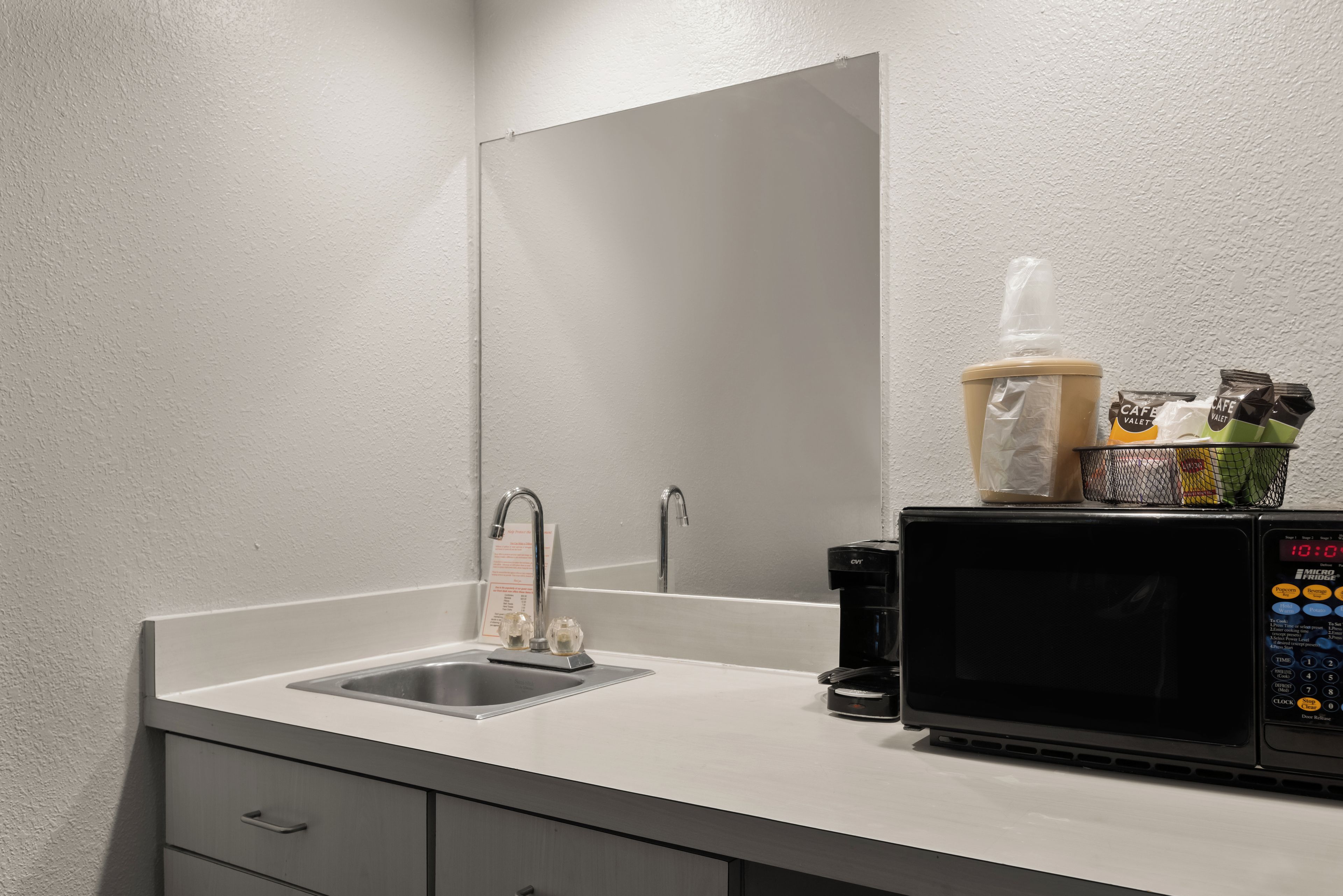 A modern bathroom with a sink, mirror, and a coffee machine.