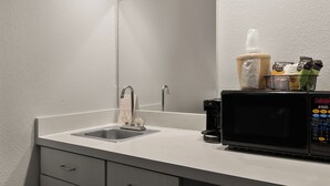 A modern bathroom with a sink, mirror, and a coffee machine. - Red Roof Inn & Suites Savannah Airport (Pooler)