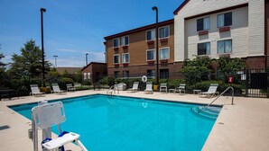 A swimming pool with a lifeguard chair, lounge chairs, and a fence. - Red Roof Inn & Suites Savannah Airport (Pooler)