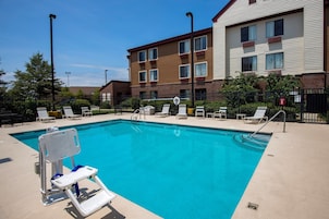 A swimming pool with a lifeguard chair, lounge chairs, and a fence.