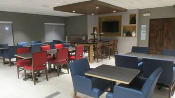 A conference room with multiple tables and chairs, a large screen, and a wooden accent wall.