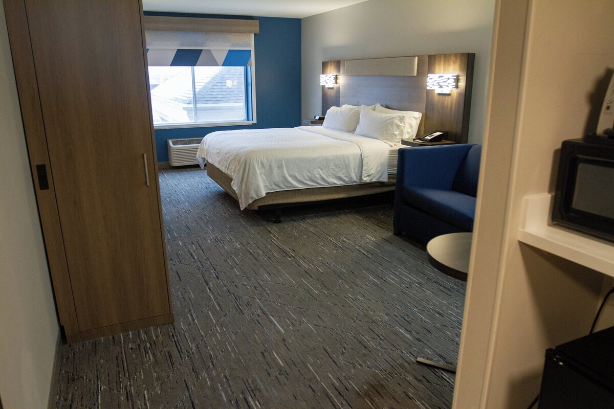 A hotel room with a bed, a desk, a chair, and a television.