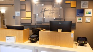 A Holiday Inn Express reception desk with two computer monitors, a cash register, and a payment terminal. - Holiday Inn Express Oneill by IHG (O'Neill)