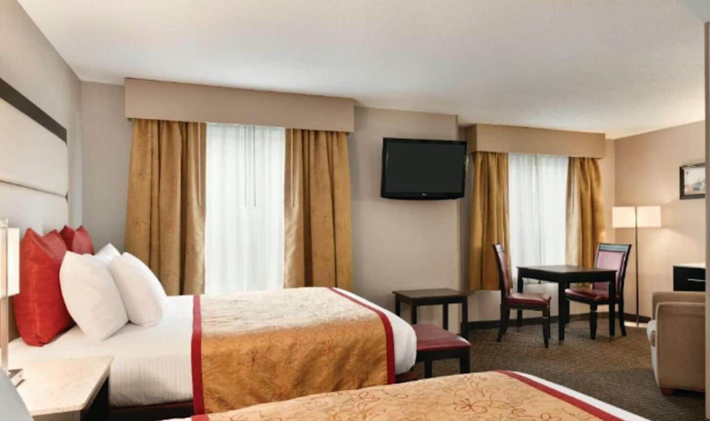 A hotel room with two beds, a television, a desk, and a chair.