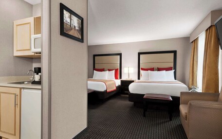 A hotel room with two beds, a desk, and a chair.