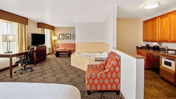 A hotel room with a bed, desk, chair, sofa, and a kitchenette. - La Quinta Inn & Suites by Wyndham Las Vegas Red Rock (Las Vegas)