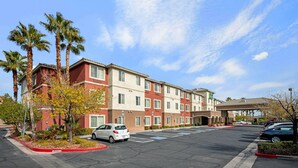 A multi-story hotel with a parking lot, palm trees, and a clear sky. - La Quinta Inn & Suites by Wyndham Las Vegas Red Rock (Las Vegas)