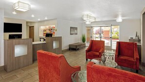A hotel lobby with a reception desk, seating area, and a large window offering a view of the outdoors. - La Quinta Inn & Suites by Wyndham Las Vegas Red Rock (Las Vegas)