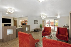 A hotel lobby with a reception desk, seating area, and a large window offering a view of the outdoors. - La Quinta Inn & Suites by Wyndham Las Vegas Red Rock (Las Vegas)