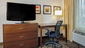 A hotel room with a flat-screen TV, a desk with a chair, a lamp, and framed pictures on the wall. - La Quinta Inn & Suites by Wyndham Las Vegas Red Rock (Las Vegas)