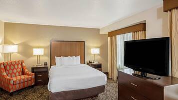 A hotel room with a bed, a TV, a chair, and two bedside tables with lamps.
