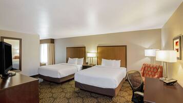 Camera d'albergo con due letti, una scrivania, una sedia, una televisione e una lampada.