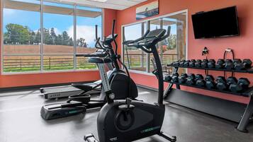 A gym with treadmills, an elliptical, and a rack of dumbbells.